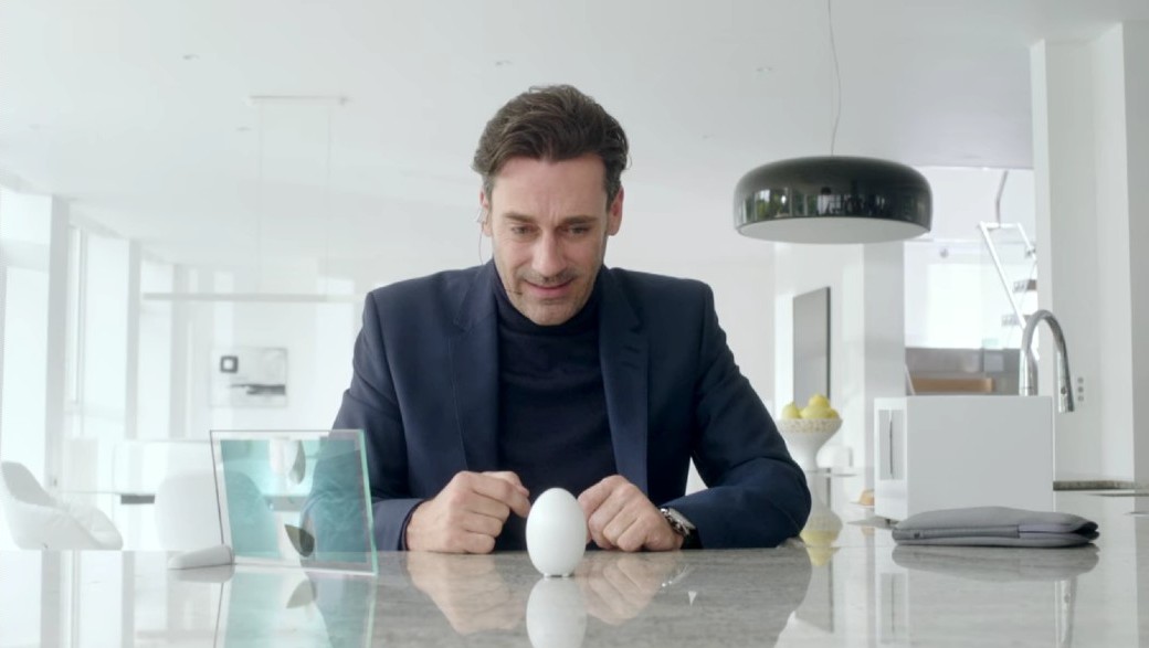 Cena de Black Mirror, homem de paletó sentado em frente a uma mesa de mármore com um ovo em pé à sua frente