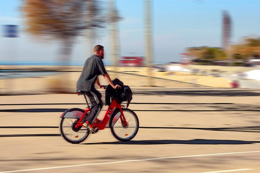 Homem anda em uma bicicleta vermelha na rua