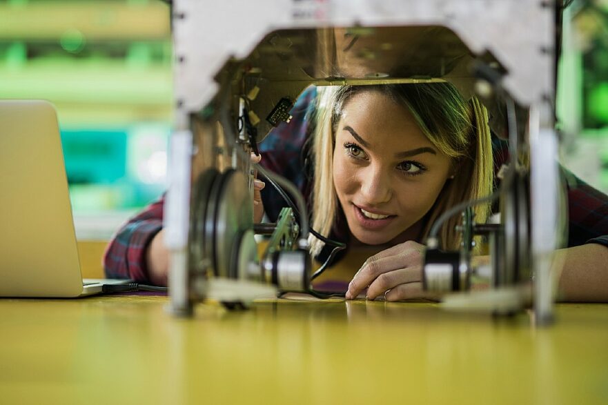 mulher jovem olha sob a base de um robô
