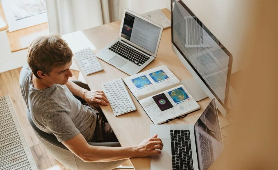 homem jovem diante do computador com mais notebook e tela