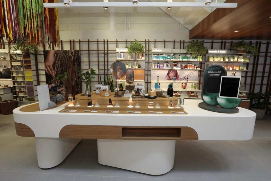 Imagem mostra mesa com itens de perfumaria e beleza e um aparelho que permite a testagem de perfumes