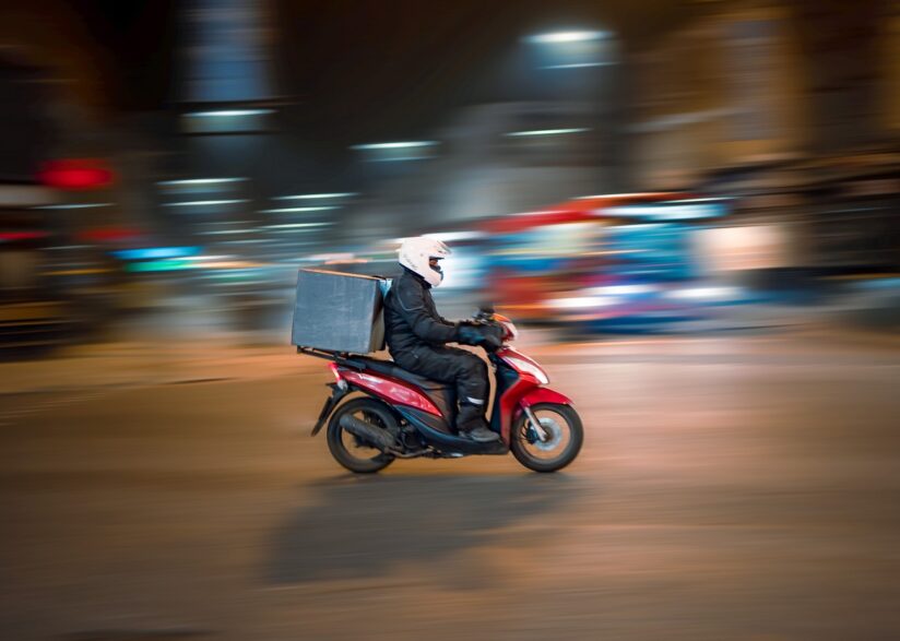 Homem em moto vermelha aparece trafegando pela cidade