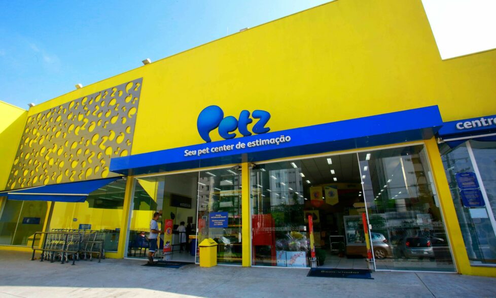 Imagem mostra a fachada de um pet shop chamado Petz. O prédio é amarelo com detalhes azuis e possui um letreiro escrito Petz em azul na parede
