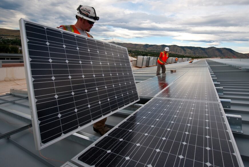 Imagem mostra homens instalando placas solares ao ar livre