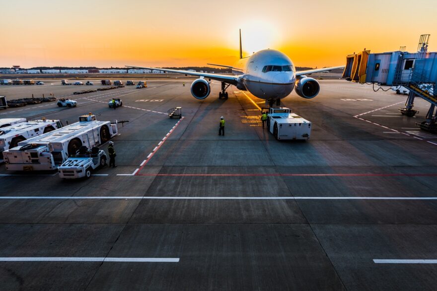 Imagem mostra um avião estacionado em um portão no por do sol