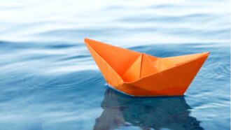 barquinho de papel laranja navega em águas calmas