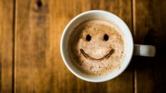 xícara de café com desenho de cara sorridente
