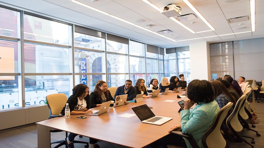 Imagem mostra uma sala de reuniões com uma equipe diversa