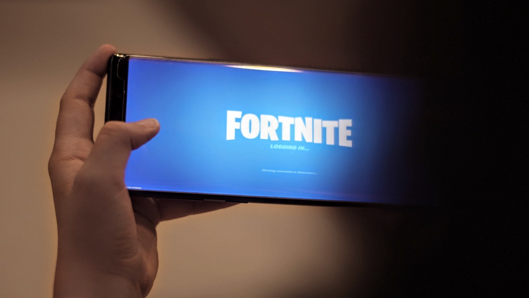 Imagem mostra uma mão segurando um celular com o jogo Fortnite aberto