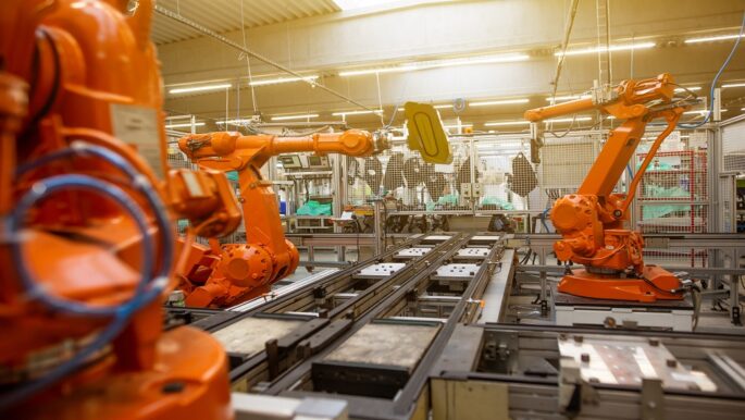 Imagem mostra braços mecânicos trabalhando em uma indústria